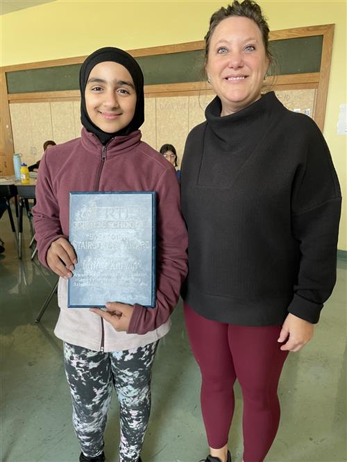 Malak Kanbar, Diehl's November Stairclimber, poses with her plaque and a school staff member.